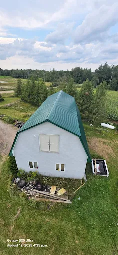 Aerial view of a gambrel-roof building with green metal roof