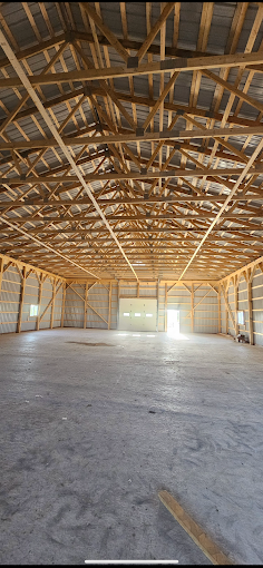 Interior of a post-frame building showing timber truss roof structure