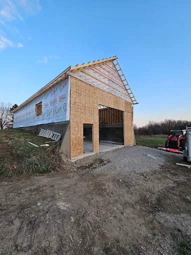 Post-frame building with sheathing and timber gable under a blue sky