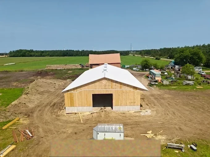 White-roof post-frame barn under construction on a rural property