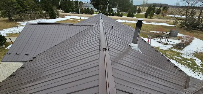 Standing-seam steel hip roof in bronze on a rural home